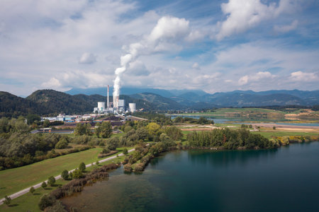 Smoking chimney at thermal power plant near lake and green nature. Aerial viewの写真素材