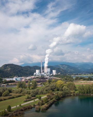 Smoking chimney at thermal power plant near lake and green nature. Aerial viewの写真素材