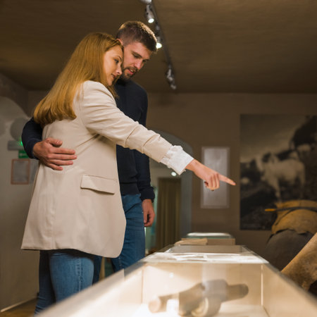 Happy young tourist couple visiting and looking exhibition in history museum exhibit.の写真素材