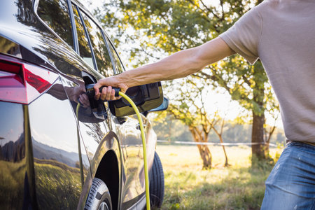 Man at EV charging station for electric car in concept of green renewable energy and eco power produced from sustainable sources.の写真素材