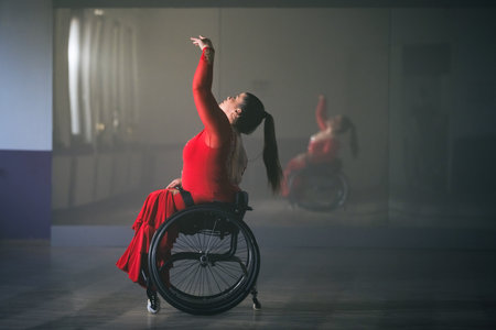 Female wheelchair dancer performing beautiful elegant choreography at a dance studio. Disability sport concept.の写真素材