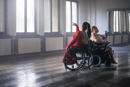 Two women with a disability, wheelchair dancers practicing dance performance in a ballroom. Dancesport and accessibility concept.の写真素材