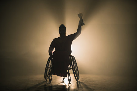 Woman with disability hoisting a trophy in the air to celebrate a sports victory and accomplishment. Success concepts.の写真素材