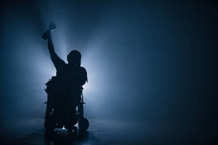 Woman with disability receiving a victory cup while sitting in a wheelchair in a dark room with one white backlight.の写真素材