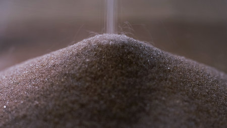 Golden glittering sand grains on the pile, leaking streaming sand of hourglass, macro shot. Passing...