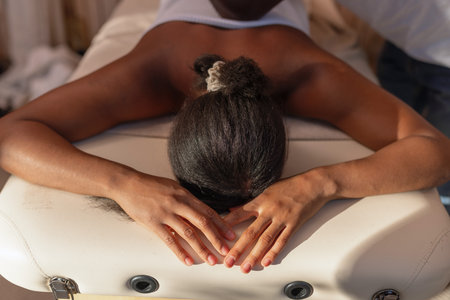 Professional African American masseur providing a relaxing massage to a female client, a luxury glamping resort guest.の写真素材