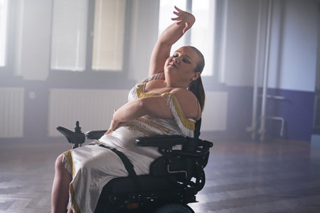 Woman on electric wheelchair performing para dance choreography. Aspiration, determination, and disability concepts.の写真素材