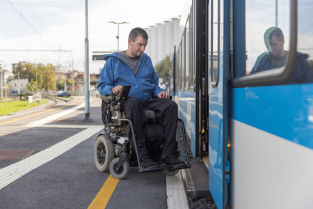 Man with disability, an electric wheelchair user entering a train. Accessible travel and inclusive transportation concepts.の写真素材