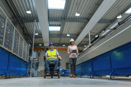 Female manager training a new employee with a disability for a job, explaining work on machines. Industry, inclusion and workplace concept.の写真素材
