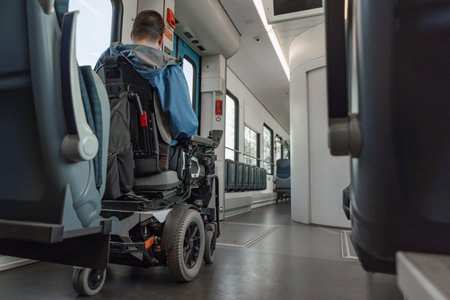 Young wheelchair user traveling by train, watching a landscape through the window. Disability, mobility, and accessibility concepts.の写真素材