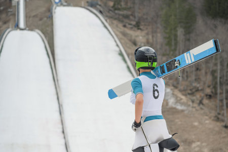 A ski jumper training on a ski jumping hill on snow in winterの写真素材