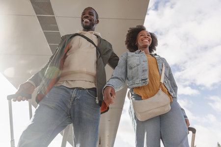 Young couple going on vacation, arriving at the railway station platform holding suitcases. Train...