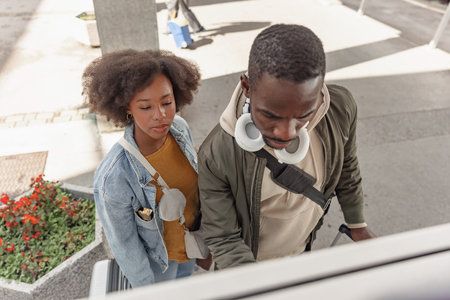 Travelers, a couple buying tickets at a train station on a vending machine, paying with a payment card.の写真素材