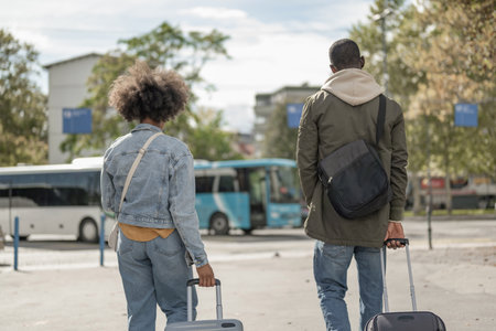 Couple on city break destination, walking with suitcases, and crossing urban streets with modern skyscrapers.の写真素材