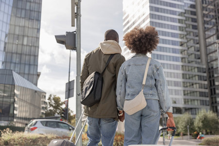 Couple on vacation in Europe, tourists with wheel suitcases crossing a busy street on their way to the city hotel.の写真素材