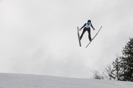 Flight moment of a ski jumper over the snow hill, skier in the air. Soaring through the sky concept.の写真素材
