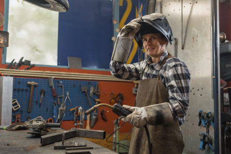 Portrait of woman welder in protective gear working in metal workshop.の写真素材