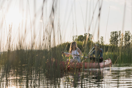 Happy couple enjoying a summer canoe ride on the lake, relaxing surrounded by beautiful green nature. Canoeing trip concepts.の写真素材