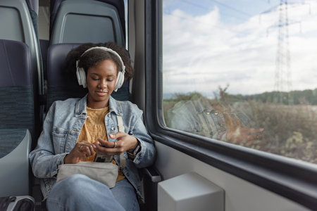 Smiling young woman enjoying her rail journey and comfortable traveling, looking out the train...