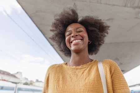 African American woman waiting for a train on a railway station platform. Solo traveling lifestyles concept.の写真素材