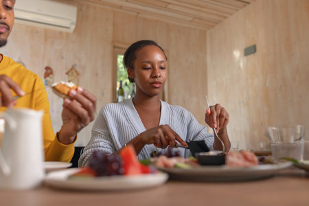 Two friends, an African American young man and a woman on a resort vacation, chatting relaxing, and enjoying breakfast together.の写真素材