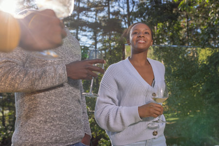 Friends having fun, dancing, talking, and enjoying good wine in a beautiful glamping resort nature on a pleasant sunny day.の写真素材