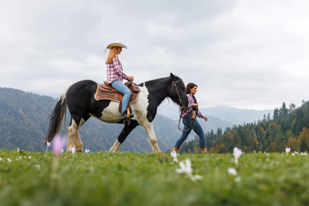 Girl on a horse ride adventure in misty mountains, horseback lesson in scenic nature setting at riding school with experienced cowgirl instructorの写真素材