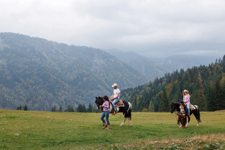 Participants in a western riding school interact with their horses under the guidance of experienced instructors, in a serene alpine settingの写真素材