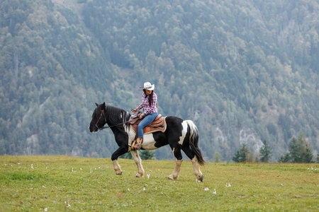 Stunning scene of a skilled cowgirl riding a pinto horse through the misty beauty of the mountain...