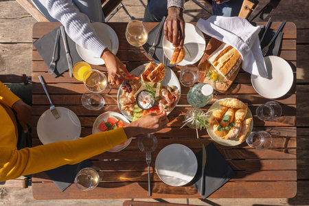 Friends enjoying their vacation, eating lunch outdoor terrace of a glamping resort surrounded by...