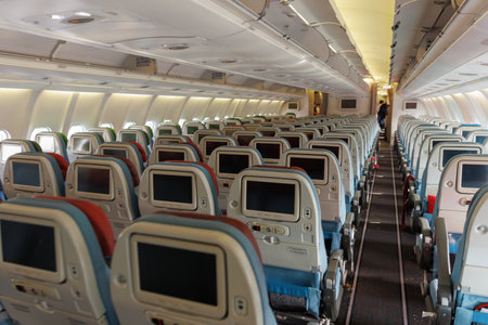 Rows of empty seats are visible within the airplane cabin, highlighting the airlines seating arrangement and onboard amenities. Soft lighting and a narrow aisle create a calm atmosphere.の写真素材