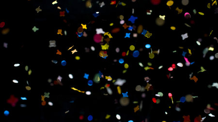 Brightly colored confetti flutters through the air, creating a festive atmosphere against a dark background.の写真素材