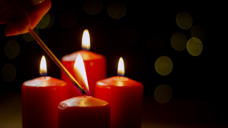 Flames flicker as Advent candle is lit, creating a warm ambiance in a cozy setting during the evening hours.の写真素材