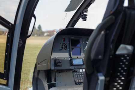 Inside view of a helicopter cockpit with controls and screens set for an upcoming flight over an open field.の写真素材
