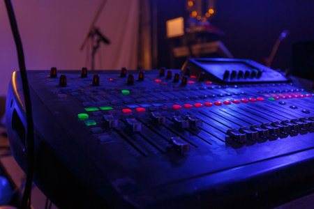 Colorful buttons and sliders on a sound mixer illuminate during a live music performance at night.の写真素材