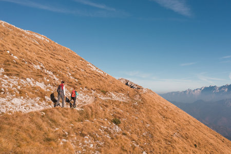 Mountaineer couple with backpacks and trekking poles doing a high mountain route on a nice sunny day. Seasonal vacation concept.の写真素材