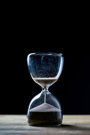 Golden sand leaking through the hourglass, measuring the passage of time, close up shot. Deadline,...