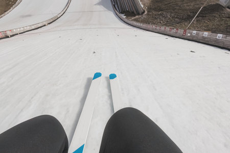 Point of view of a jumper performing a jump on the ski jumping hill, from start bar to landing on the snow.の写真素材