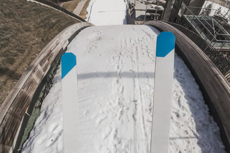 Jumper flying through the air and landing on the snow during hill ski jumping practice, point of view shot. Winter sports experience concept.の写真素材