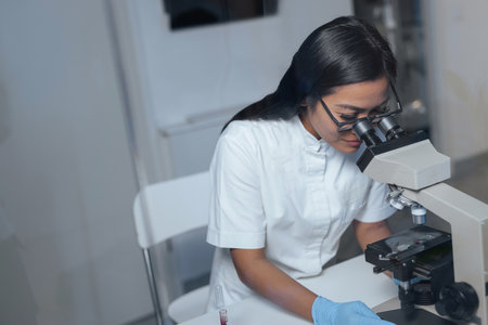 Female laboratory technician pipetting blood sample on the slide, preparing specimen for microscope...