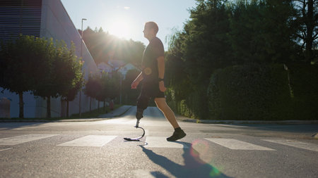 A man walks confidently across a street with a prosthetic leg, enjoying the warm sunlight and a...