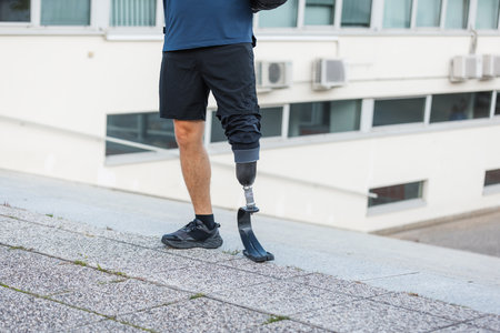 A man exercises outdoors on a sunny day, showing strength and determination with his prosthetic leg.の写真素材