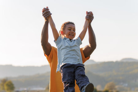 Father lifts child while they smile and enjoy outdoors together in natural light.