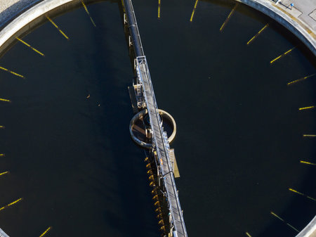 Aerial view of a modern wastewater treatment plant with large circular settling tanks and clean...