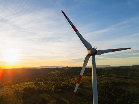 Drone captures wind turbine at sunset highlighting renewable energy and clean technology in a...