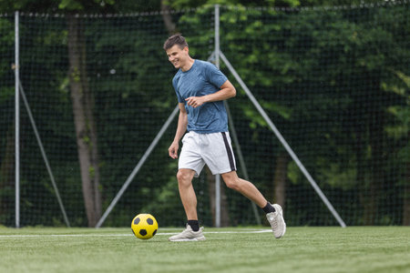 A male soccer player performs drills on the field, focusing on ball control and skills during practice under natural light.