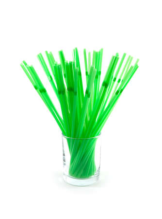 Lots of green drinking straws in the glass. White background.の写真素材