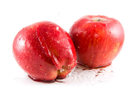 Two red apples splashing in water. White background.の写真素材
