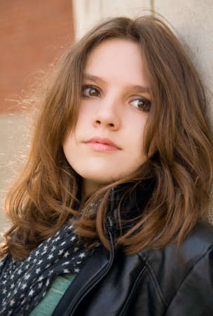 Portrait of the beautiful teenage girl on a brick background