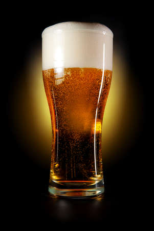 Pint glass of beer amber color with head on a black background  の写真素材